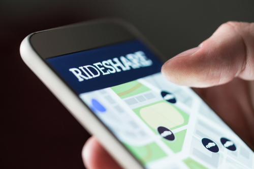 Close-up of a smartphone screen showing a rideshare app with map and vehicle icons.