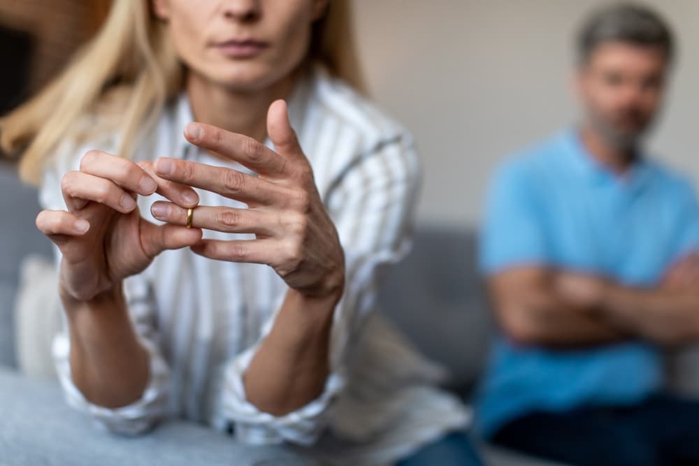 Unhappy middle aged lady takes off ring, ignoring man in a divorce process.