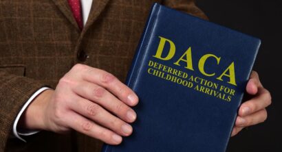 Deferred Action for Childhood Arrivals DACA concept. Man in suit shows the book.