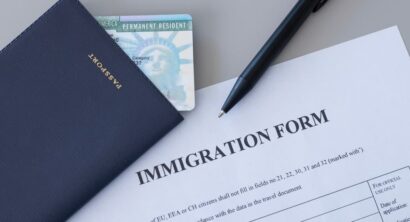 United States passport, permanent resident (green) card and immigration form on desk.