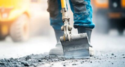 A close-up of a construction worker using a jackhammer to break concrete on a road repair site, Road construction scene, Heavy machinery operation style