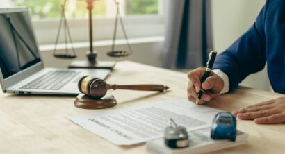 Close-up of a lawyer’s desk with a judge's gavel, a miniature car, and legal documents, symbolizing a court case or insurance claim after a car accident.