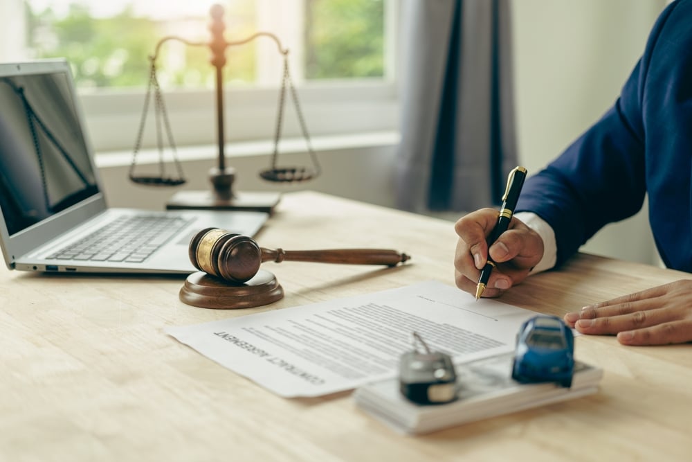 Close-up of a lawyer’s desk with a judge's gavel, a miniature car, and legal documents, symbolizing a court case or insurance claim after a car accident.