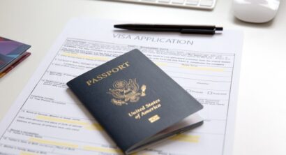 American passport with visa application documents, black pan and computer on white table