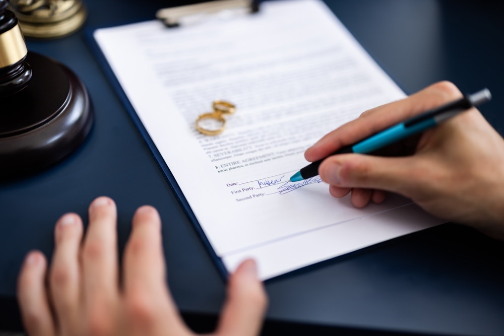 Young couple, one Caucasian and one Hispanic, consulting with a lawyer in court to sign a divorce agreement document.