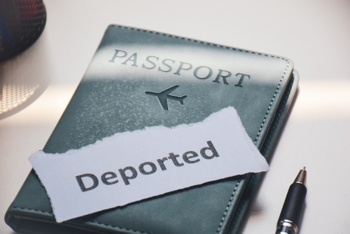 Travel passport with a torn paper reading &ldquo;Deported&rdquo; placed on top, representing deportation risk and immigration issues.
