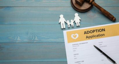 Adoption application, gavel, family figure and pen on blue wooden table,