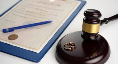 Judge gavel with wedding rings and a legal paper on table