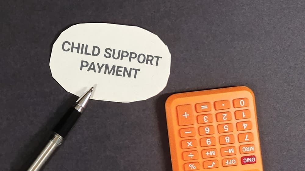 Conceptual shot highlighting child support payment, featuring a calculator and pen,
