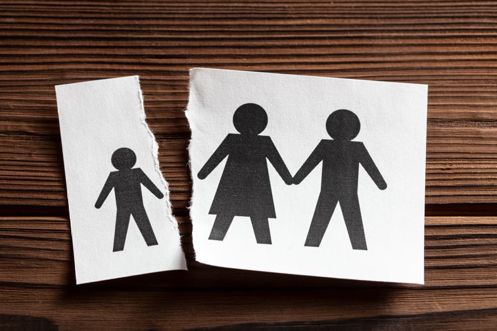 A piece of paper with parents and a torn piece of paper with a child.