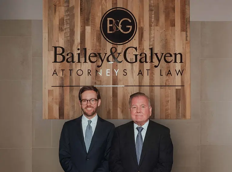 Michael and Phillip Galyen standing by Bailey & Galyen Attorneys at Law sign