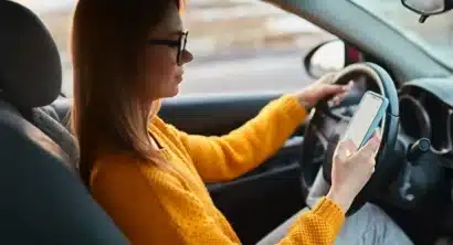 female driver distracted by looking at her cell phone